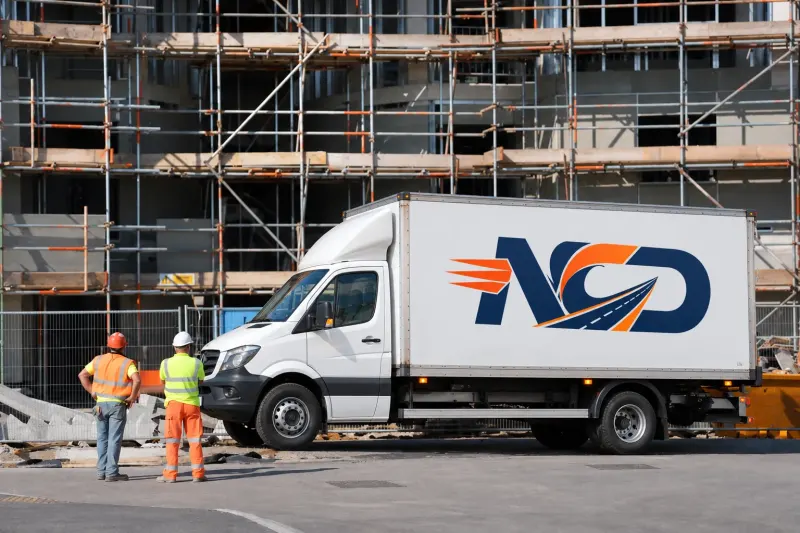 National Couriers Direct lorry delivering to a construction site with scaffolding